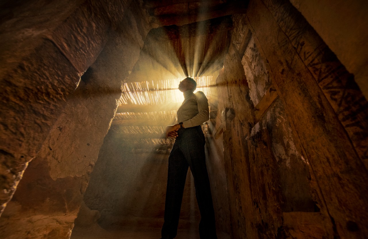 Dramatic light rays piercing through ancient tomb interior at Jabal Ikmah, AlUla