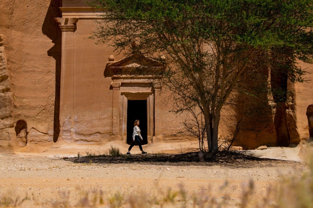 Ancient Nabataean tomb facade with doorway framed by desert tree at AlUla