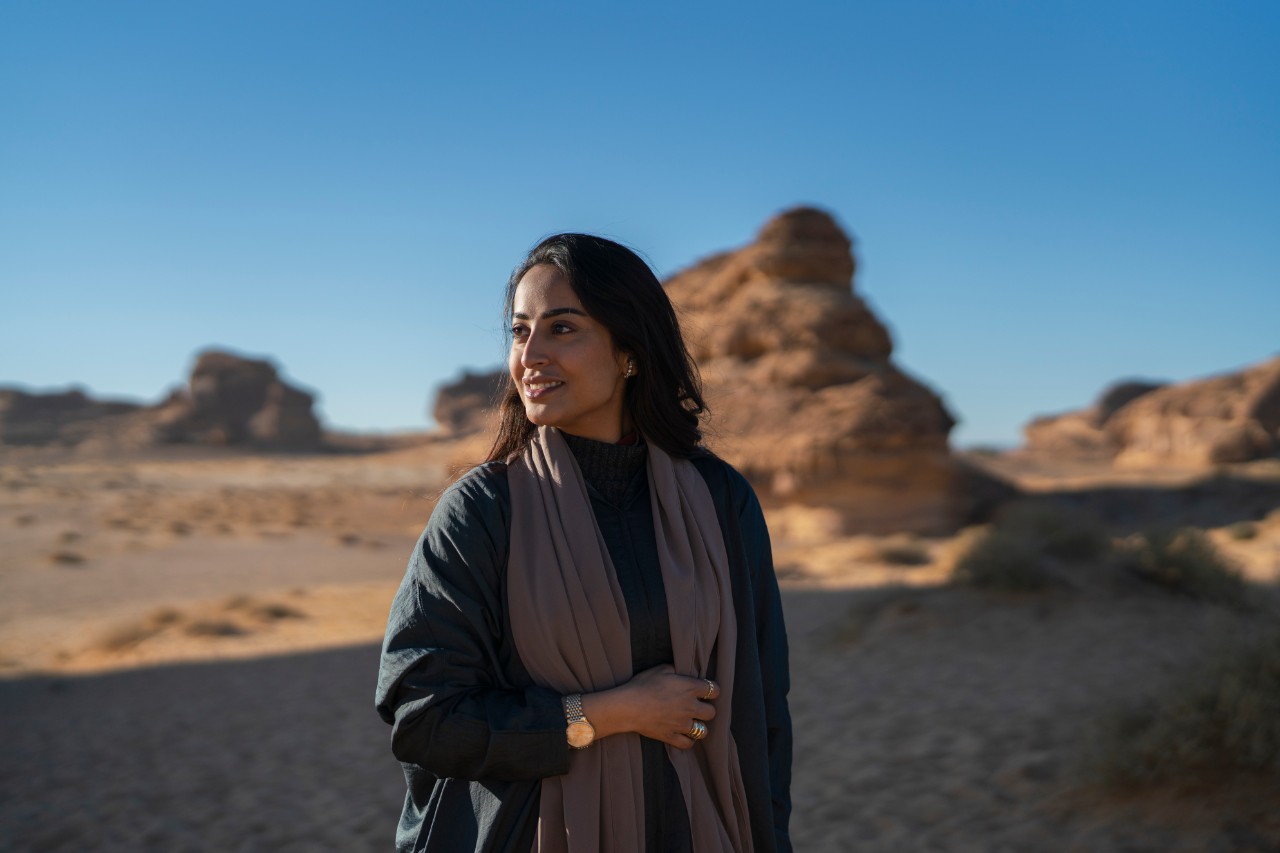 Visitor contemplating the ancient rock formations of AlUla at sunset