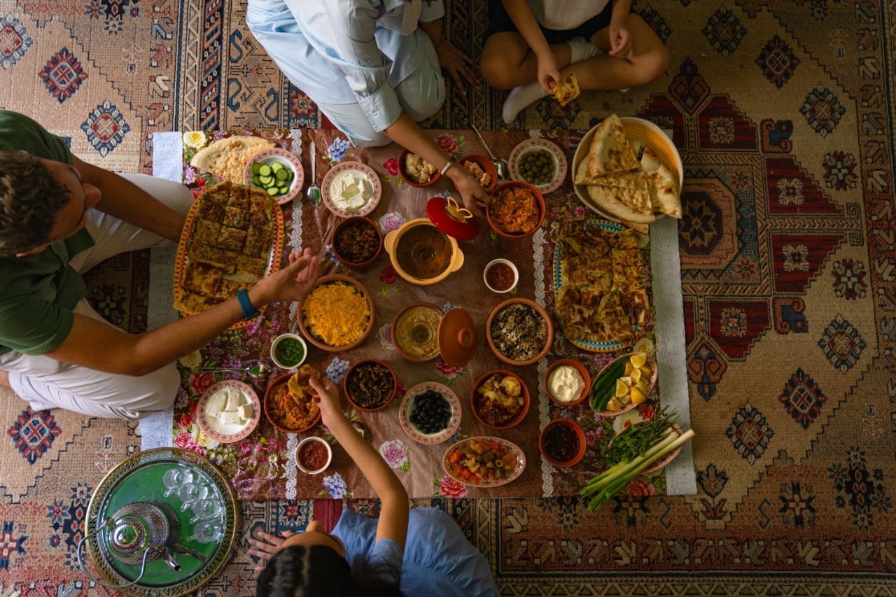 Overhead view of a traditional Arabian feast with many dishes on colorful rugs
