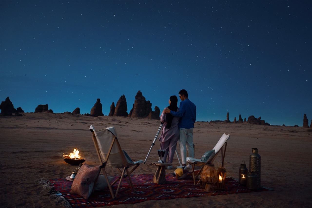 Couple with telescope observing the Milky Way through The Arch (Rainbow Rock), AlUla Saudi Arabia