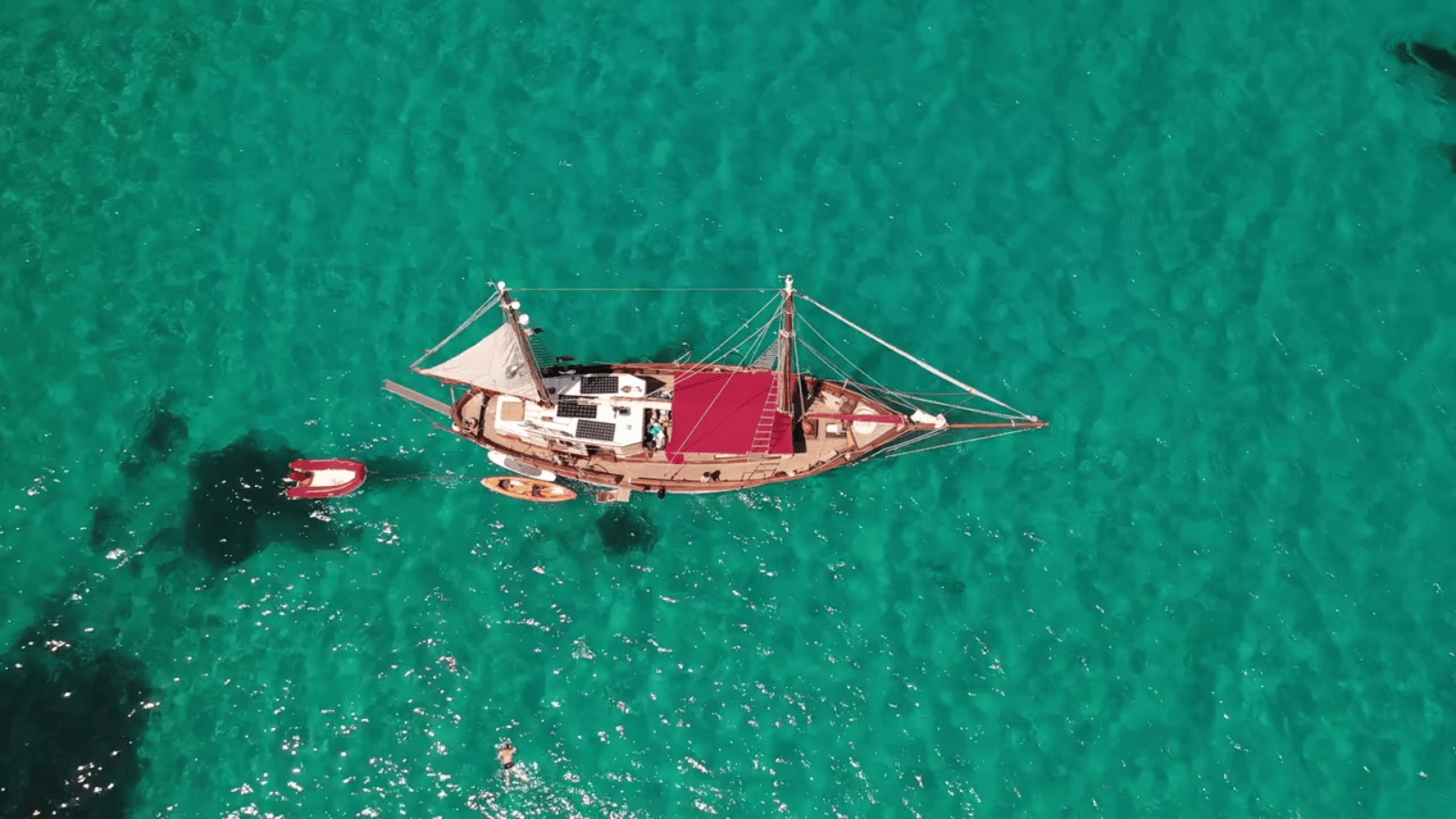 Aerial view of a traditional sailing yacht anchored in crystal-clear turquoise Red Sea waters, Saudi Arabia
