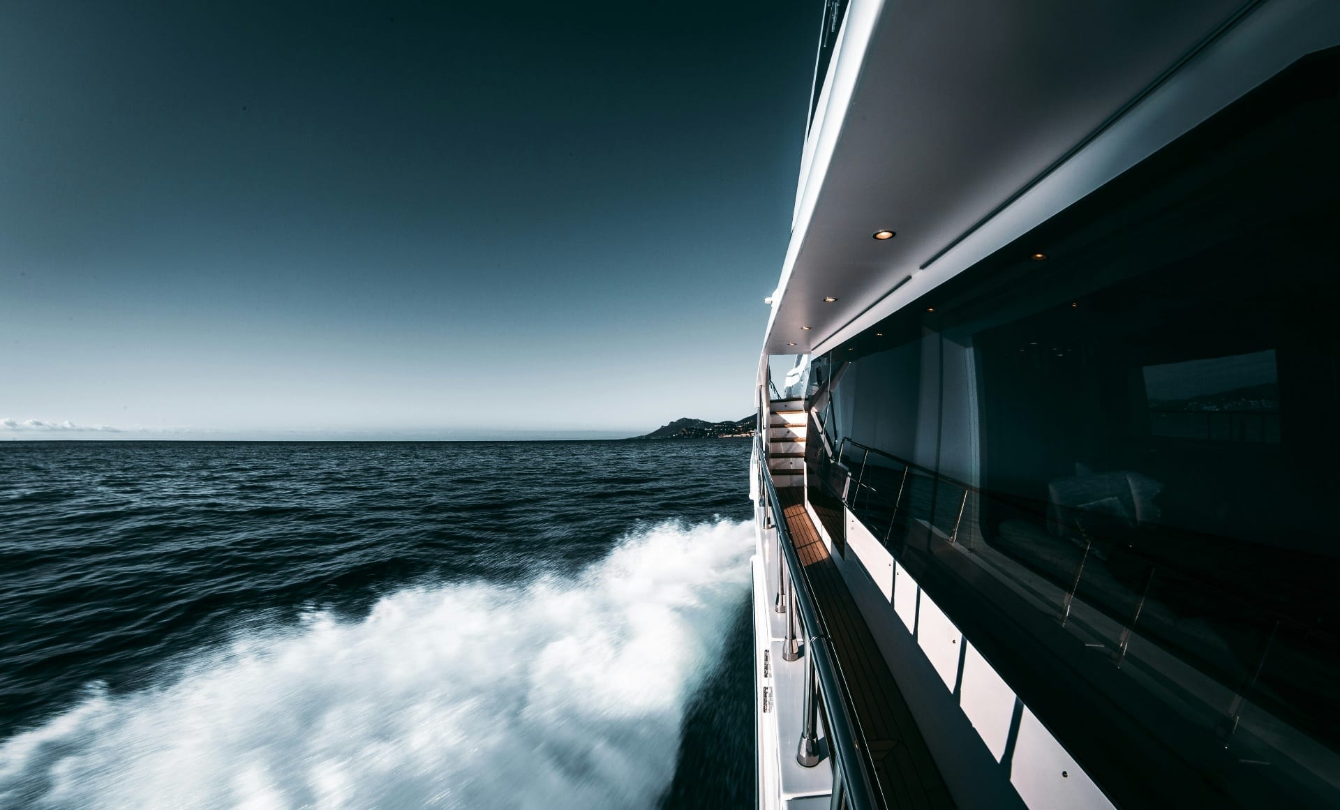 View from the deck of a luxury yacht cruising at speed through open waters at dusk