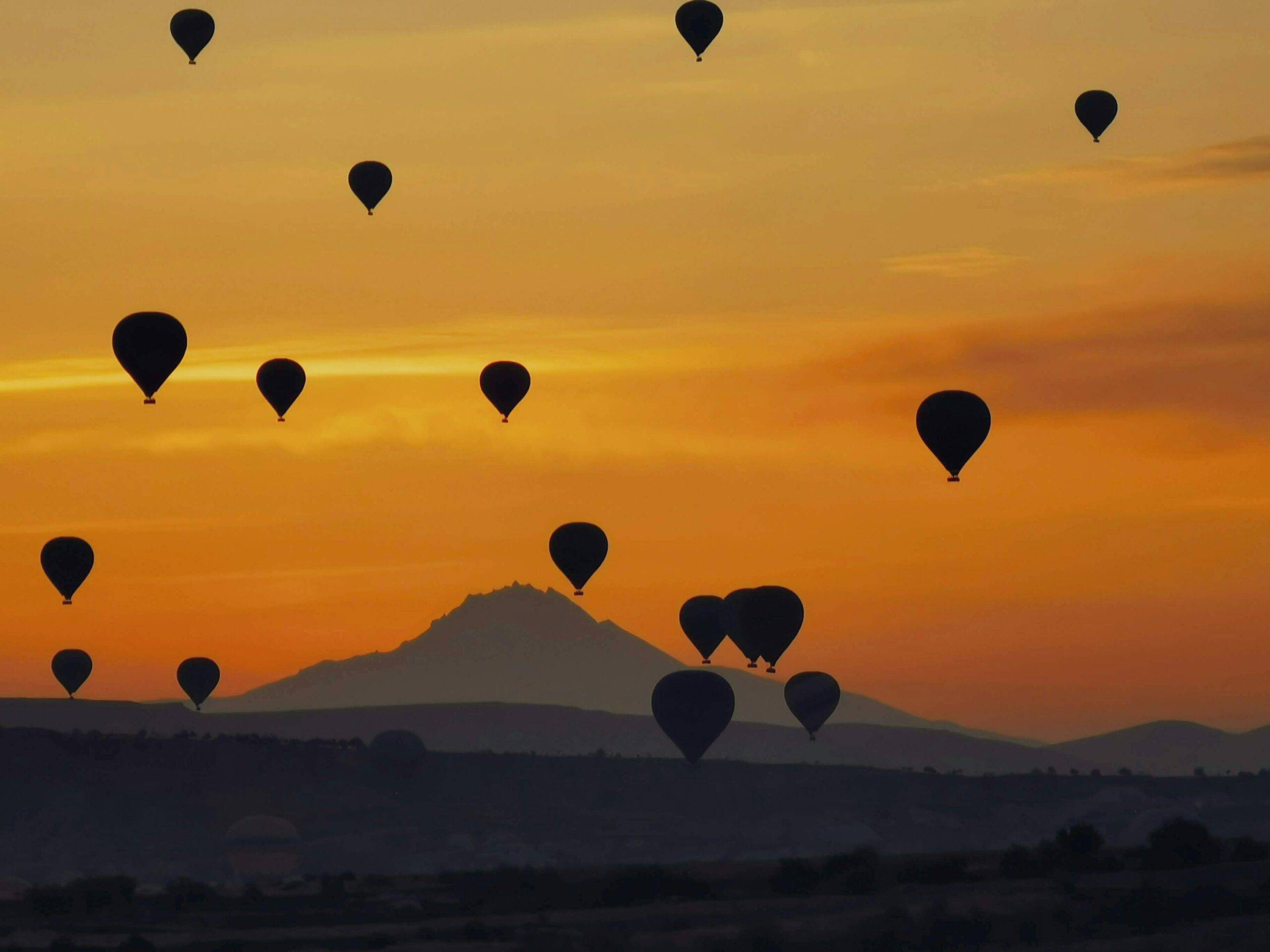 Hot-air balloons floating above AlUla rock formations at sunrise.