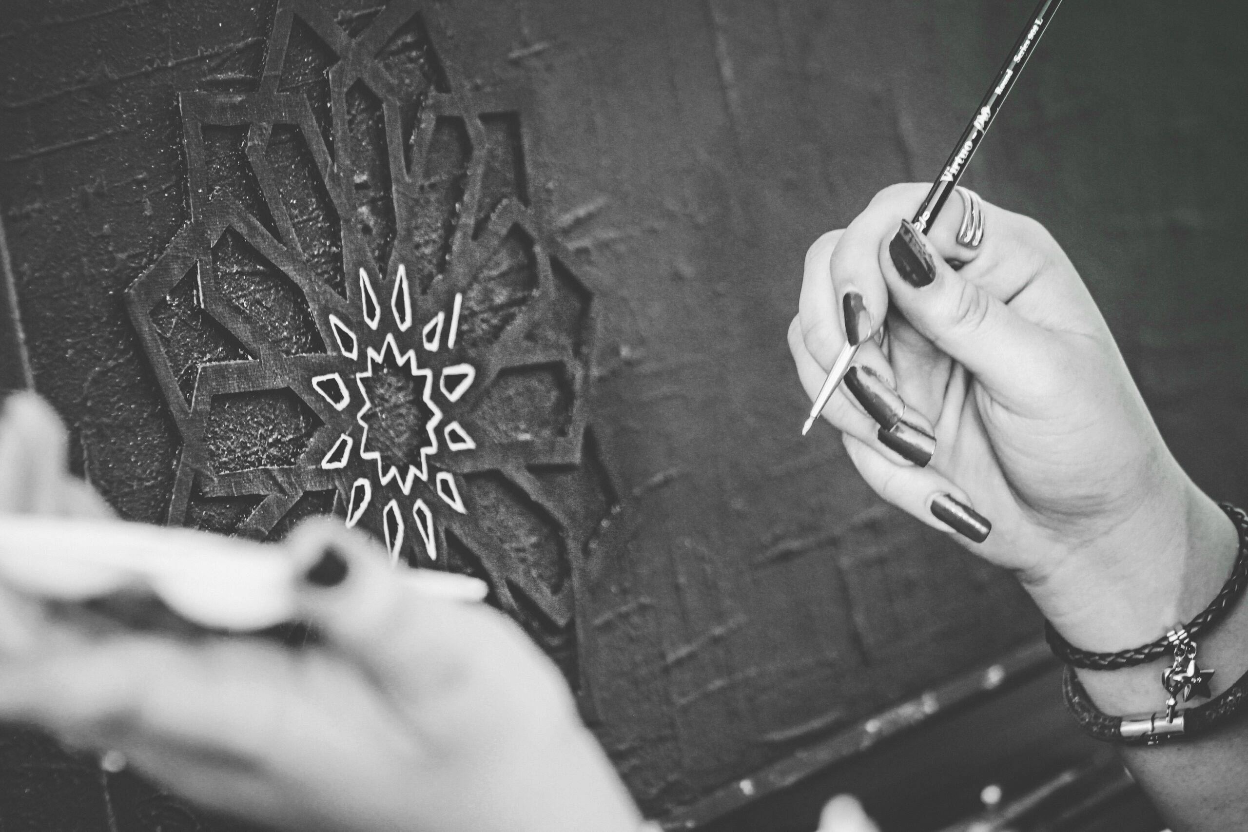 Monochrome image featuring hands creating art with a brush in Riyadh.