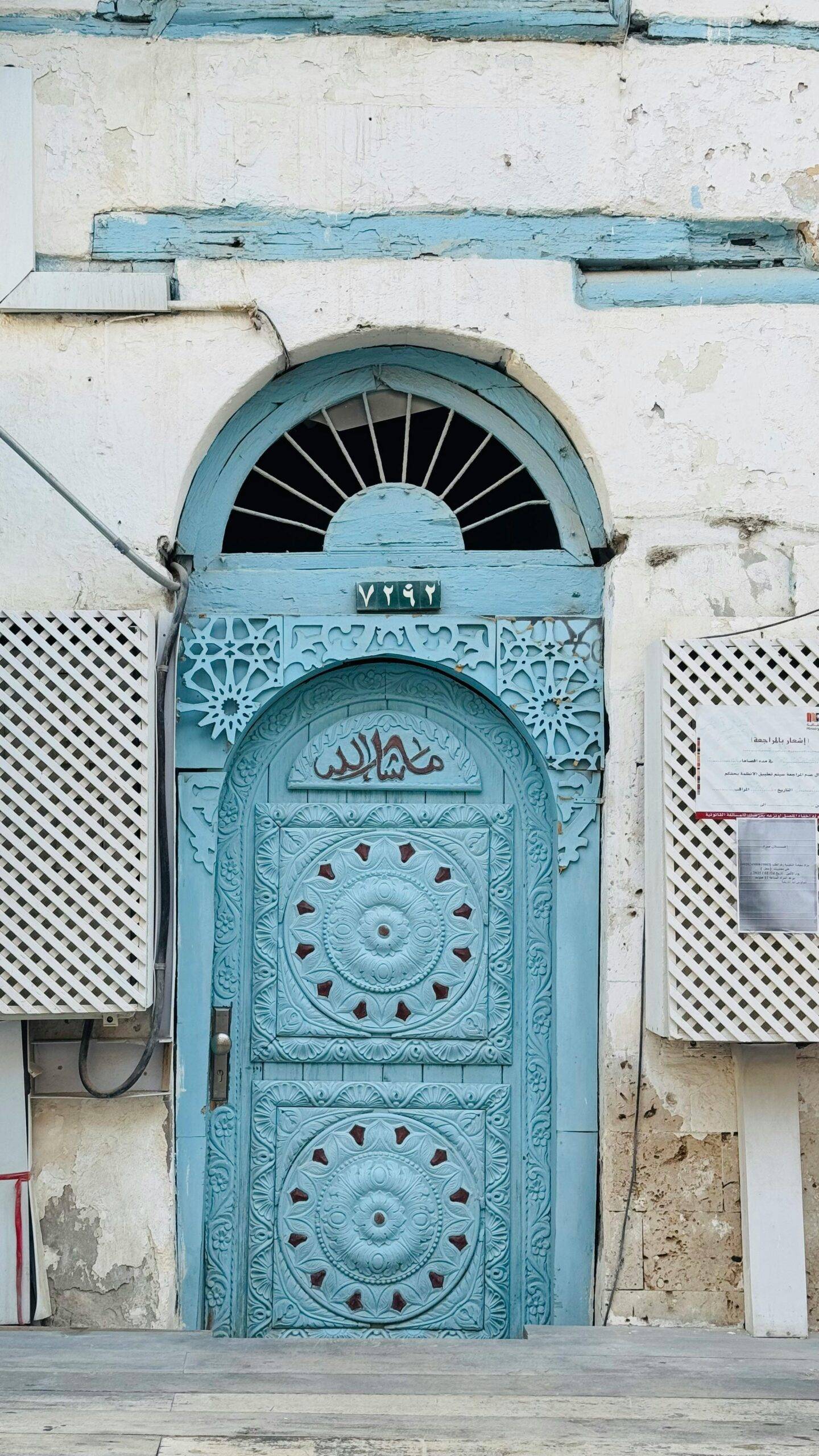 Intricate blue door with ornate designs in a historic stone building facade.