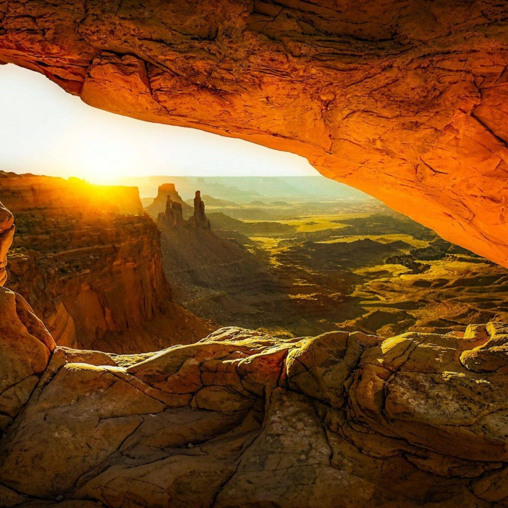 Captivating view of sunrise through Mesa Arch, showcasing breathtaking rock formations and desert landscape.